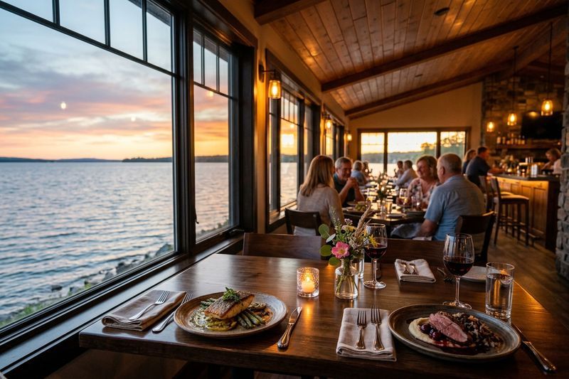 The dining room at Harbourside Inn & Grill at sunset, tables set by the windows over the water