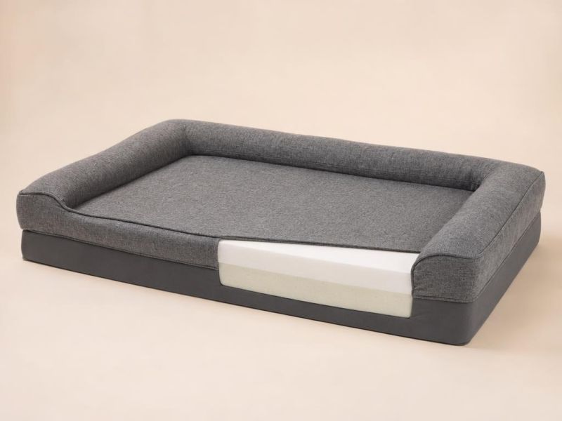 Imagen generada con IA del tipo de producto: una cama ortopédica grande de espuma con funda gris. No es la foto de la tienda; el producto real puede variar.