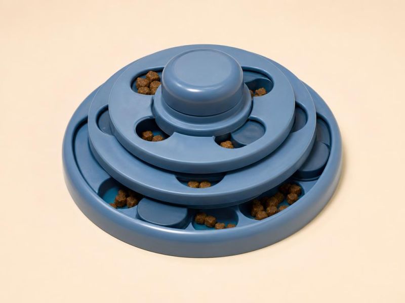 Imagen generada con IA del tipo de producto: un rompecabezas dispensador redondo azul con discos giratorios y croquetas. No es la foto de la tienda; el producto real puede variar.