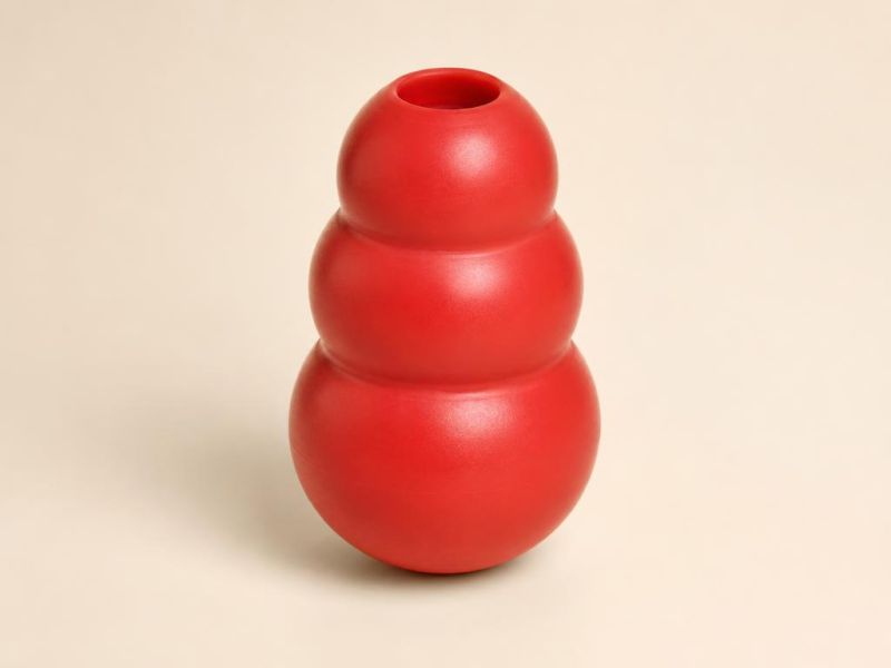 Imagen generada con IA del tipo de producto: un juguete de hule rojo rellenable, de tres segmentos redondeados. No es la foto de la tienda; el producto real puede variar.