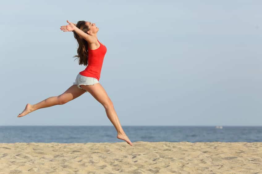 A lady leaping in joy on the beach
