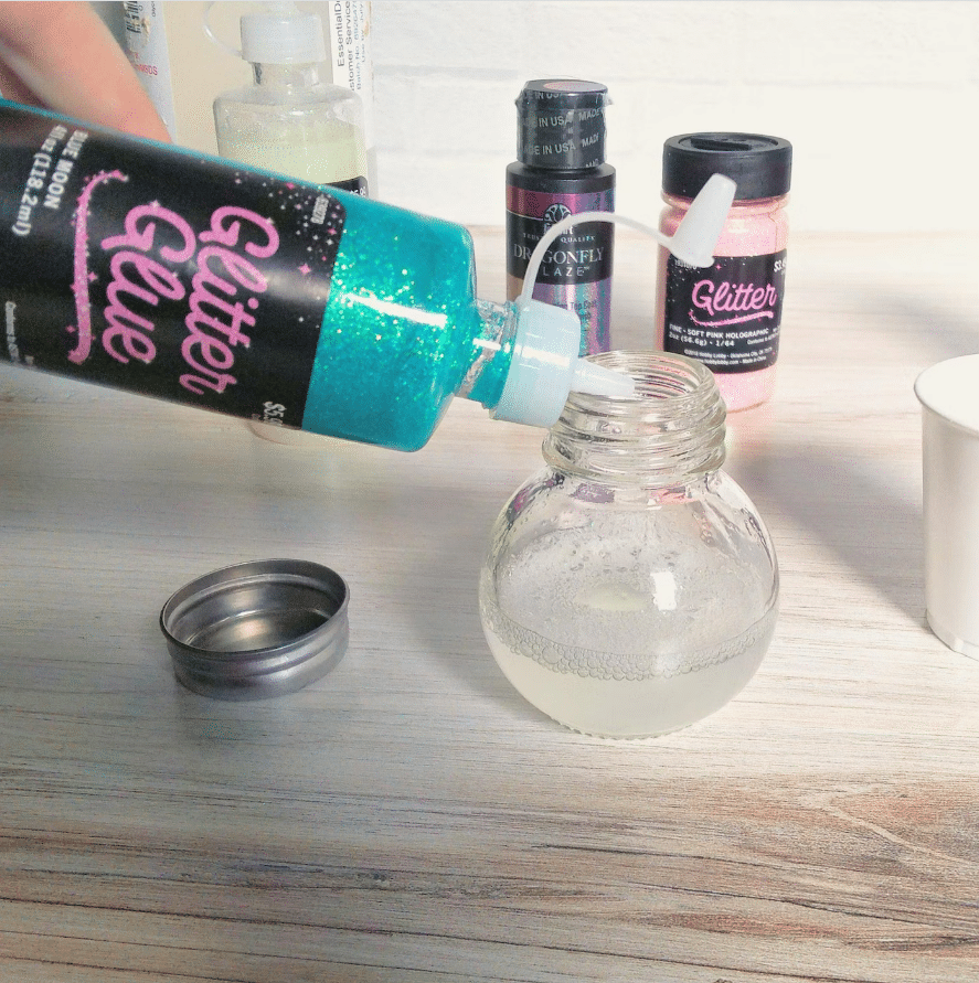 Image of adding blue glitter glue to water in jar
